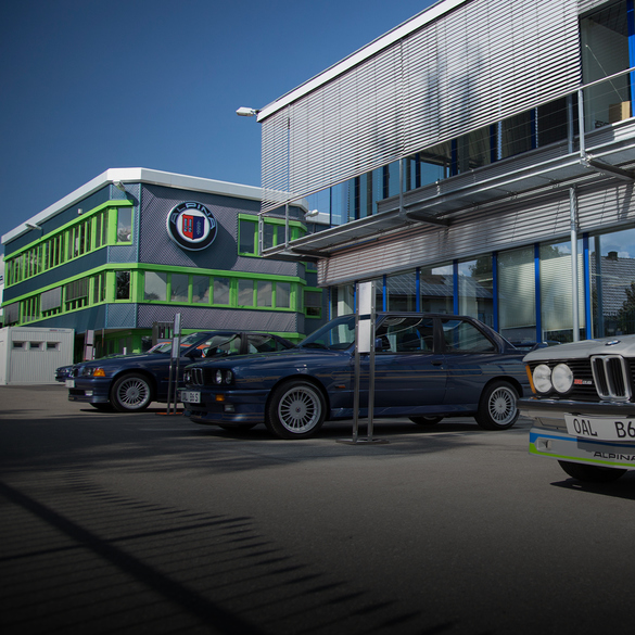 BMW ALPINA Manufaktur von außen mit davor geparkten Oldtimern.